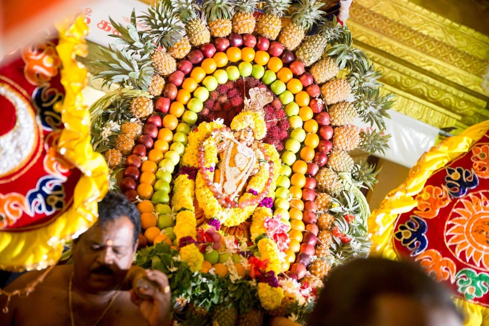Festival idol surrounded by fruit decorations during a special puja