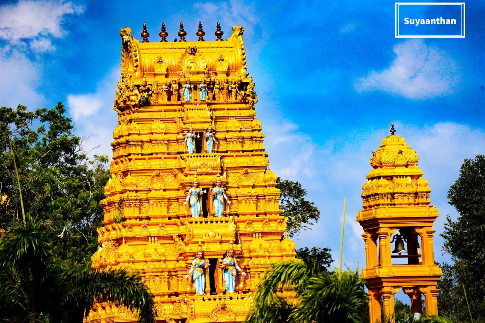 Sculpted golden gopuram against a vivid blue sky